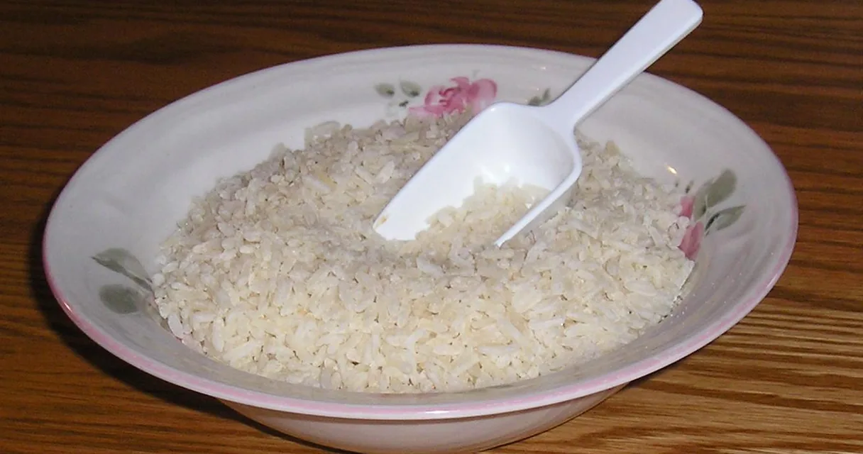 Tigela de arroz com uma pá de plástico, ilustrando quantas gramas tem uma colher de sopa